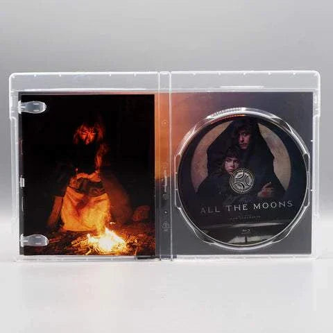 Shudder All the Moons Blu-Ray open case showing disc and cover art with a person by fire and two figures on the disc.